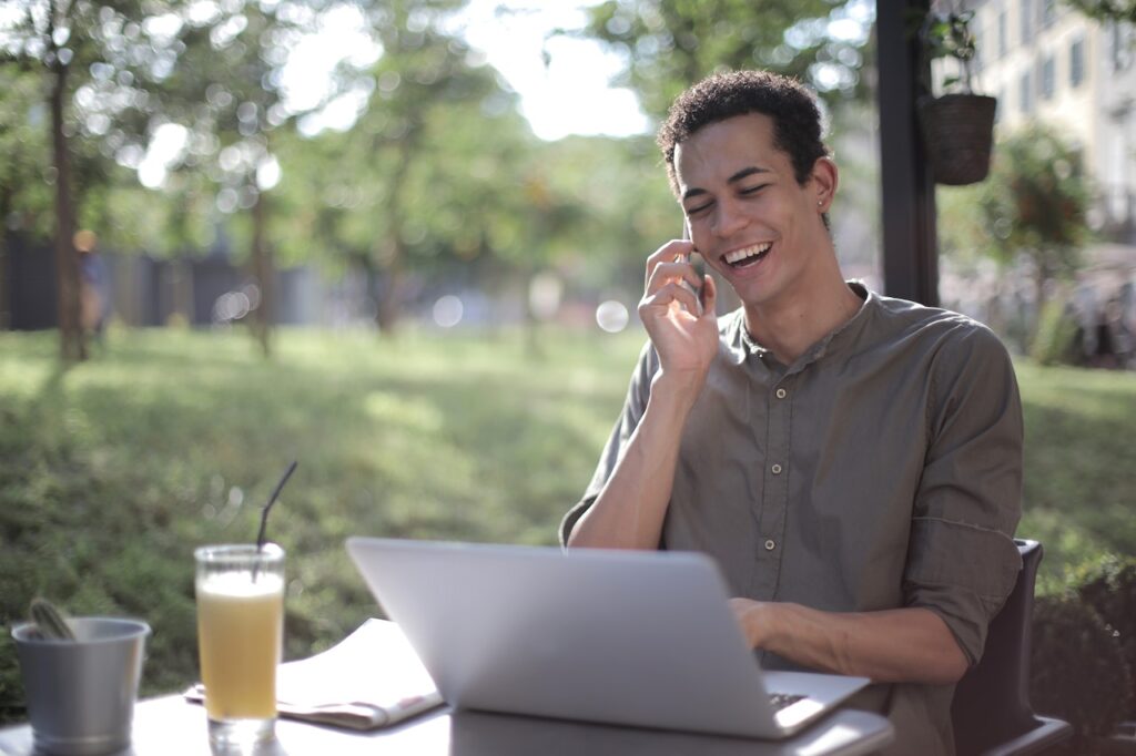 Person answering call while managing online business on his laptop